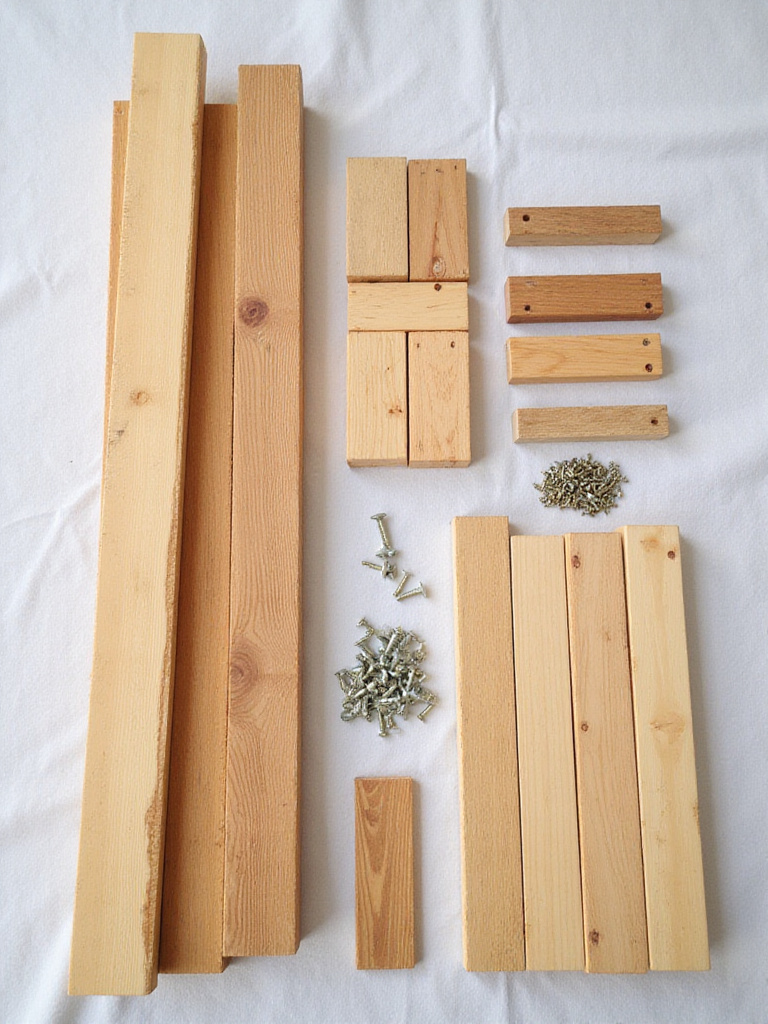 A perfectly organized collection of raw deck building materials, including neatly stacked wooden planks and fasteners, arranged on a light surface to symbolize detailed project planning and efficiency.