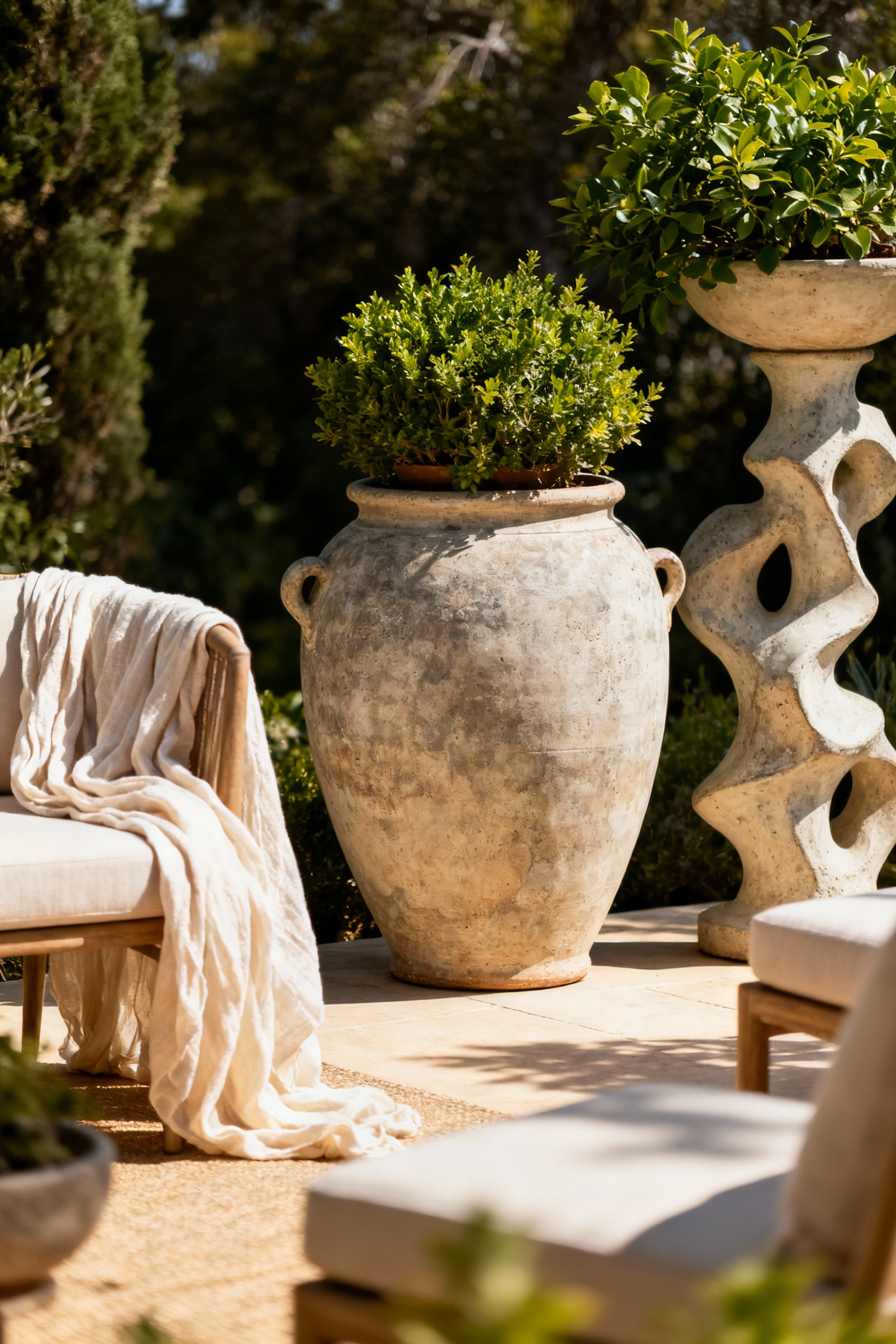 A sophisticated patio featuring substantial artisanal ceramic planters and decorative stoneware, creating visual anchors and depth among soft outdoor furnishings under natural light.