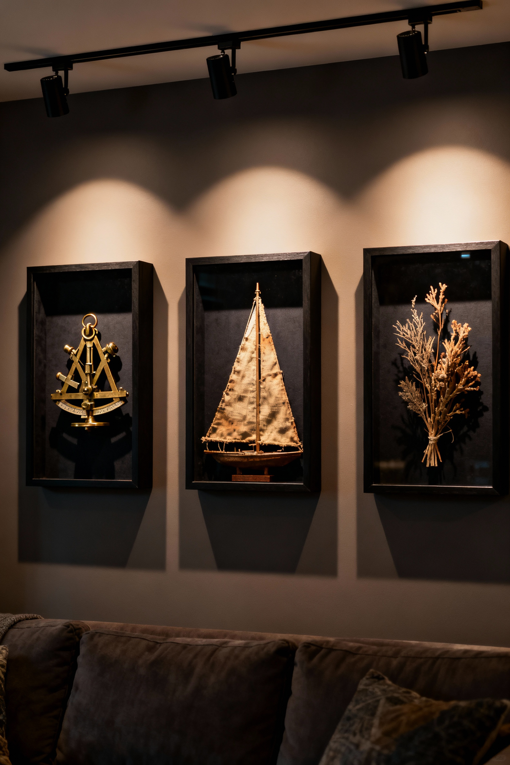 Curated gallery wall featuring three deep shadow boxes holding antique nautical and voyage mementos, illustrating how shadow boxes create texture and depth in living room decor.