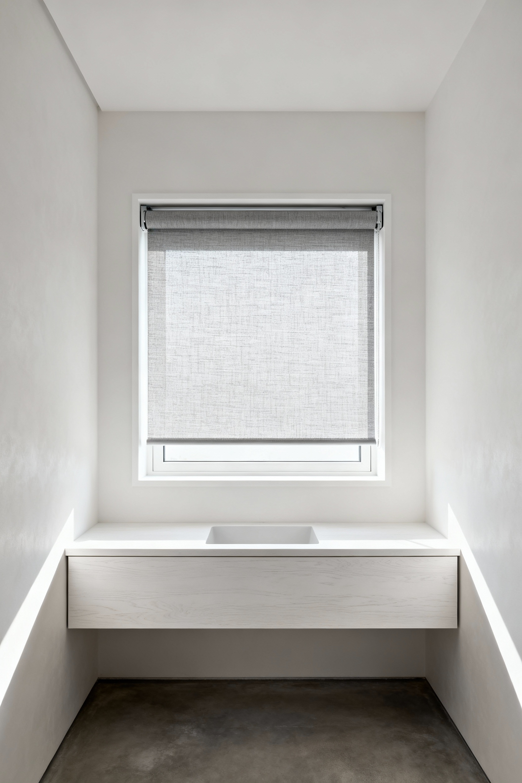 A fully recessed waterproof roller shade rolled up completely inside a flush-mount cassette system in a minimalist white bathroom window demonstrating concealed design.