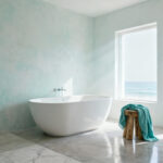Ethereal coastal bathroom with whitewashed limewash walls, a freestanding tub, soft aqua linen accents, and natural diffused light, emphasizing a serene and spacious color palette.