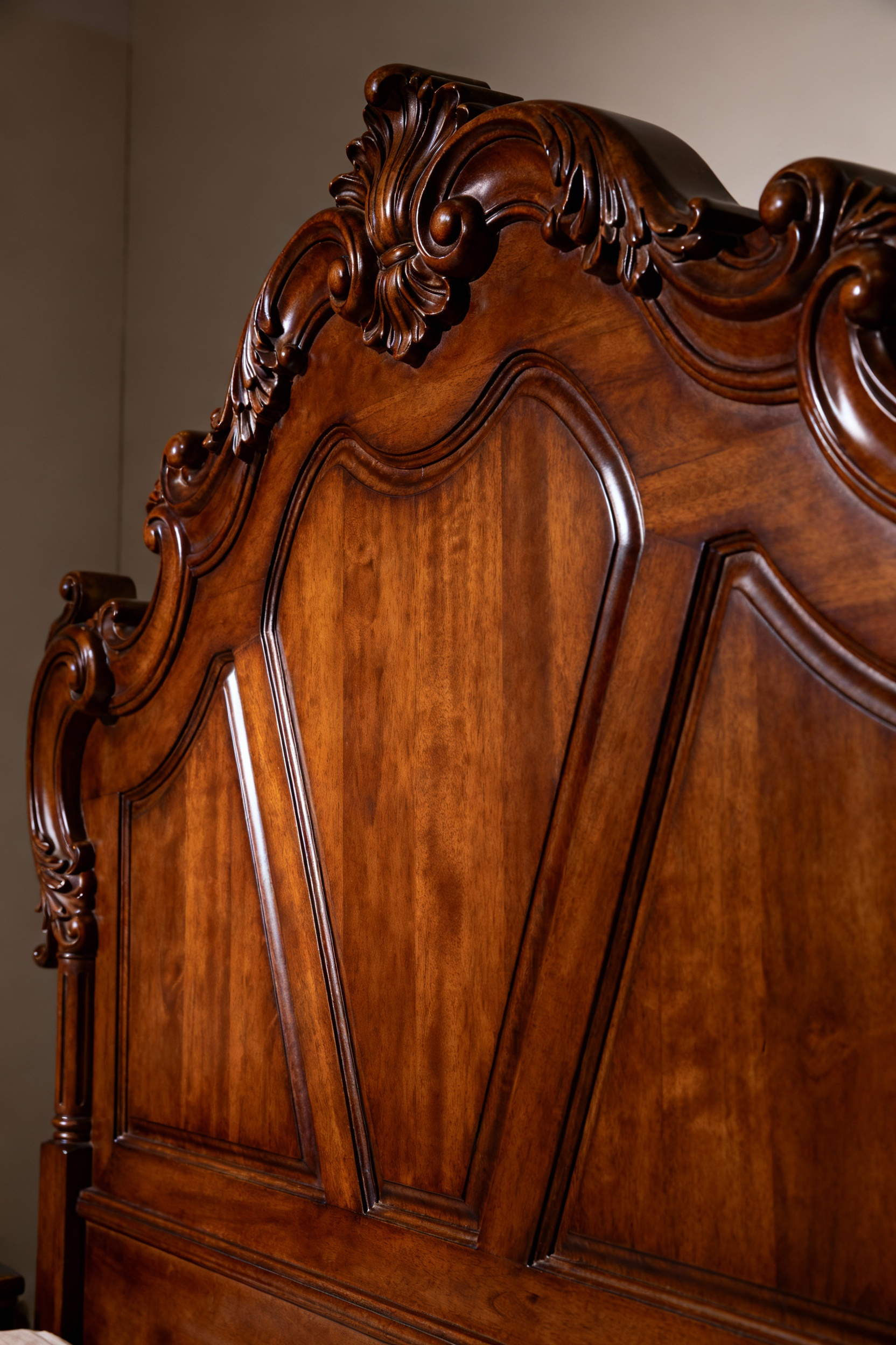 Close-up of intricate hand-carved detail on a bespoke luxury headboard, showcasing artisanal craftsmanship and rich wood grain, in a soft-lit bedroom.